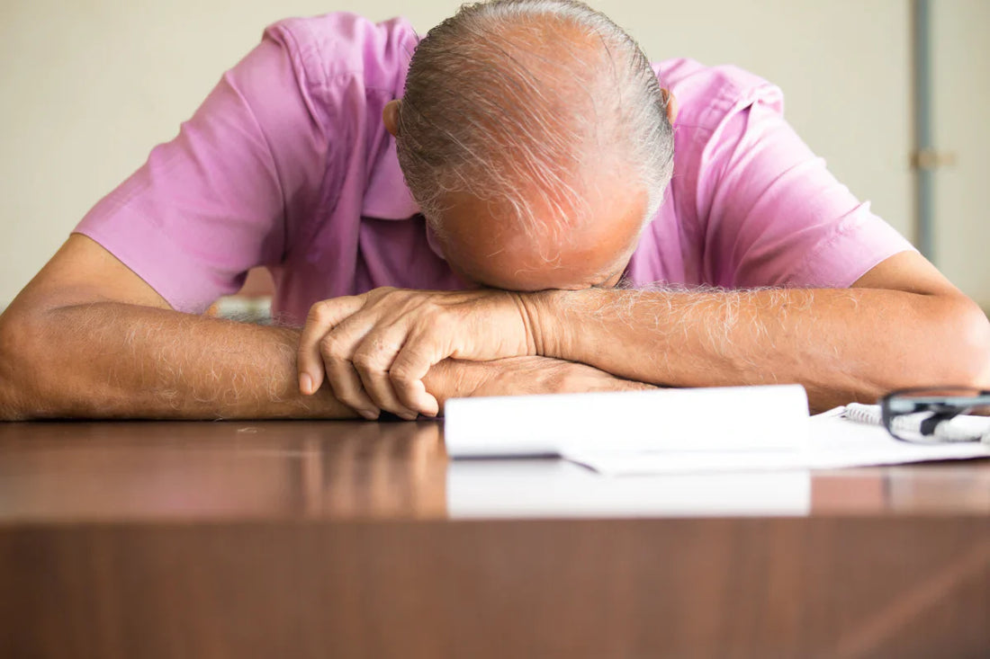 old man in pink shirt naps at table